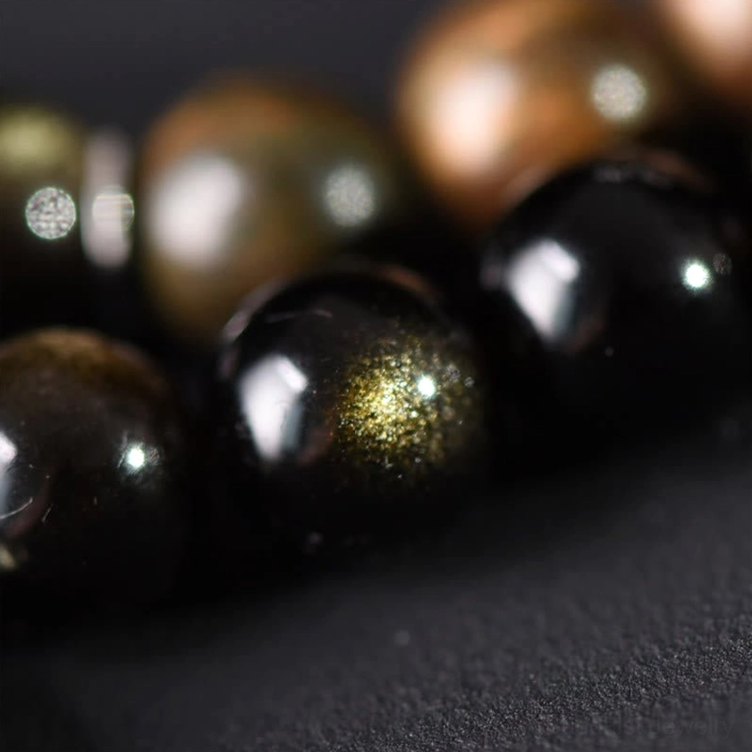 Macro close-up of glossy gold sheen obsidian beads and natural wood beads showing texture and luster