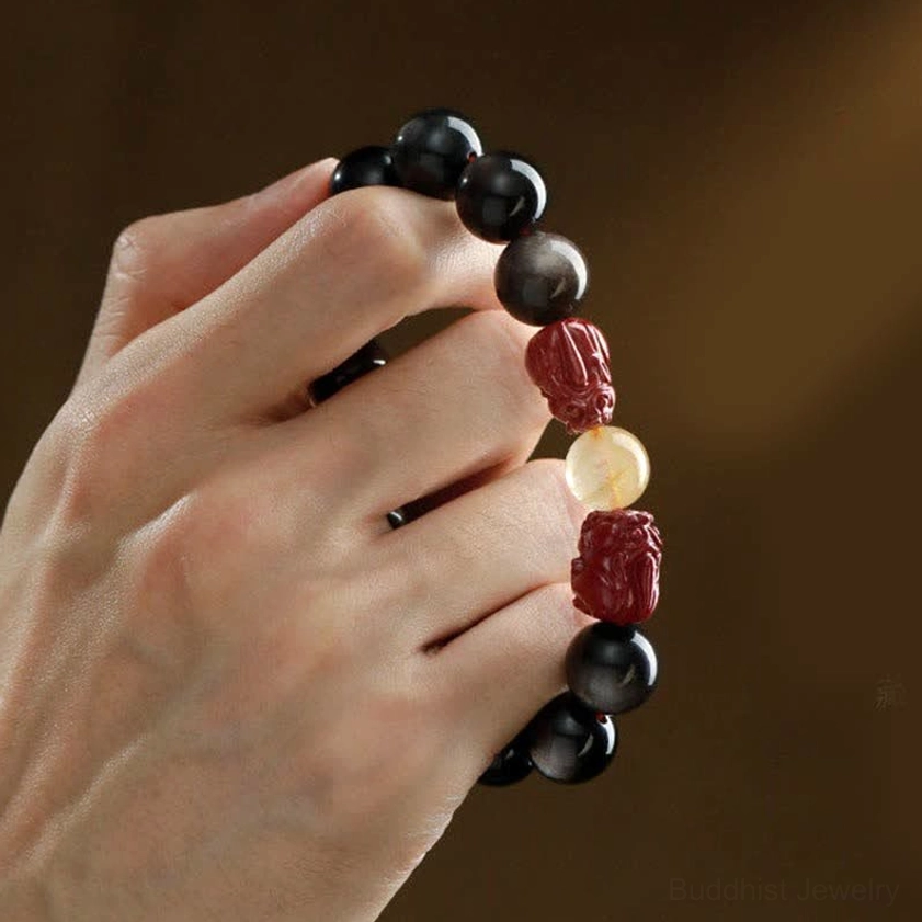 Handmade obsidian pixiu bracelet with glossy black beads and red charms on brown background