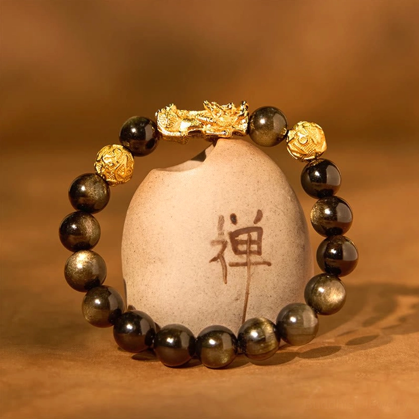 Gold sheen obsidian Pixiu Buddhist bracelet arranged in circular formation on Zen stone with Chinese character, displaying the protective charm and spiritual symbolism
