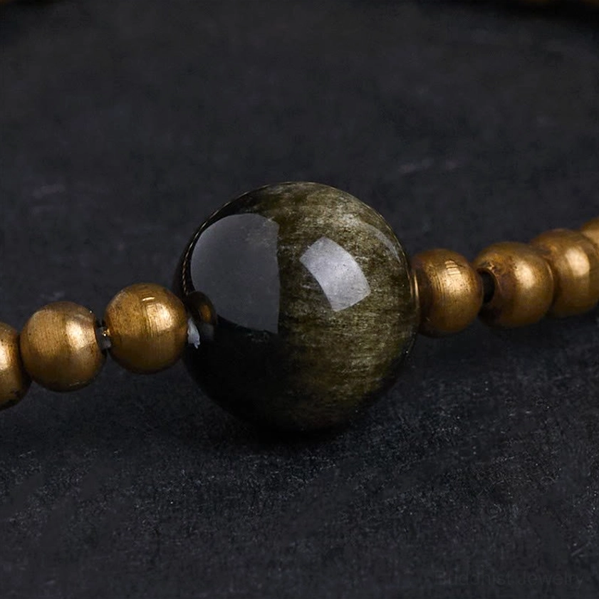 Macro photography of glossy gold sheen obsidian center bead with copper brass accent beads