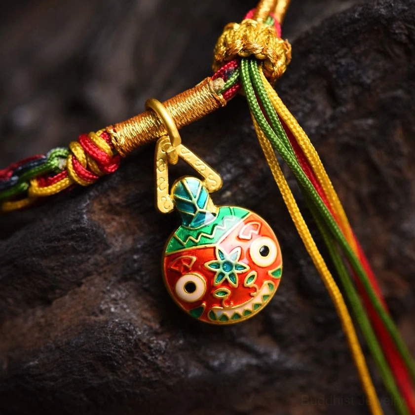 Close-up macro detail of gold swallowing beast enamel charm showing intricate design and braided knot connection