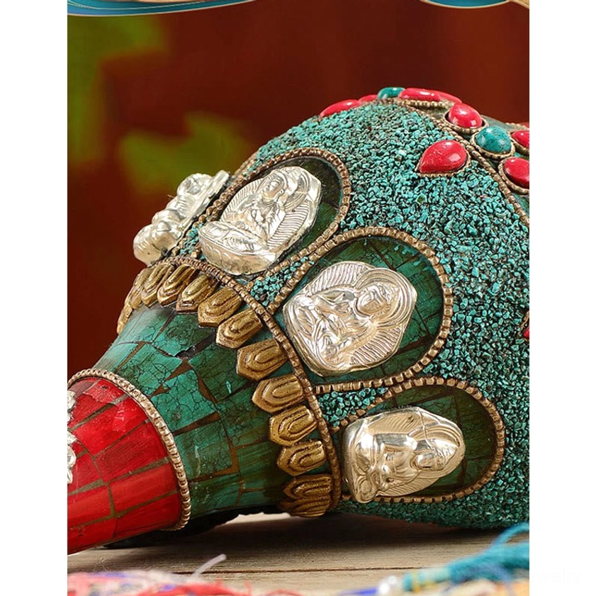 Detailed close-up of Buddhist conch shell featuring gold-trimmed Buddha medallion with turquoise and red gem accents