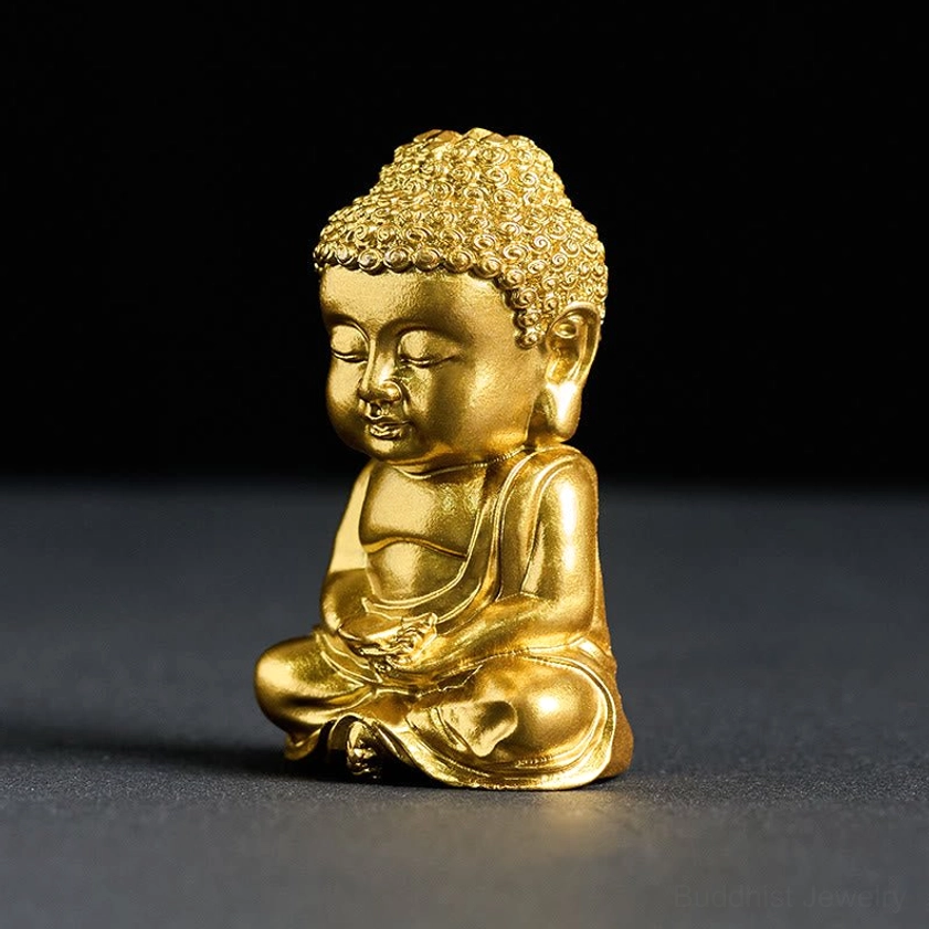 Golden Buddha figurine left side view with calm closed eyes and traditional cross-legged sitting posture