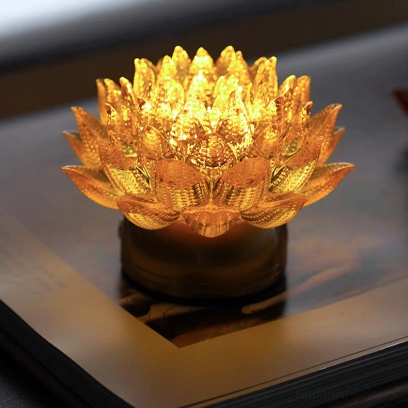 Golden lotus liuli glass illuminated sculpture with copper brass base on book, warm ambient lighting, top view showing petal details