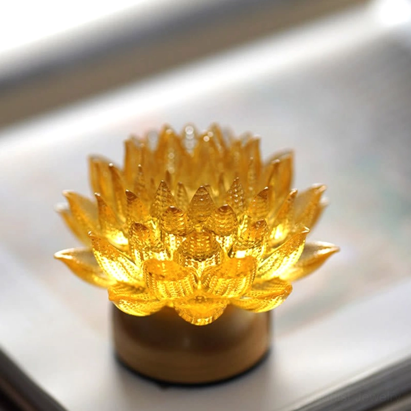 Golden lotus night light with warm glow, low front view on smooth desktop, translucent petal design