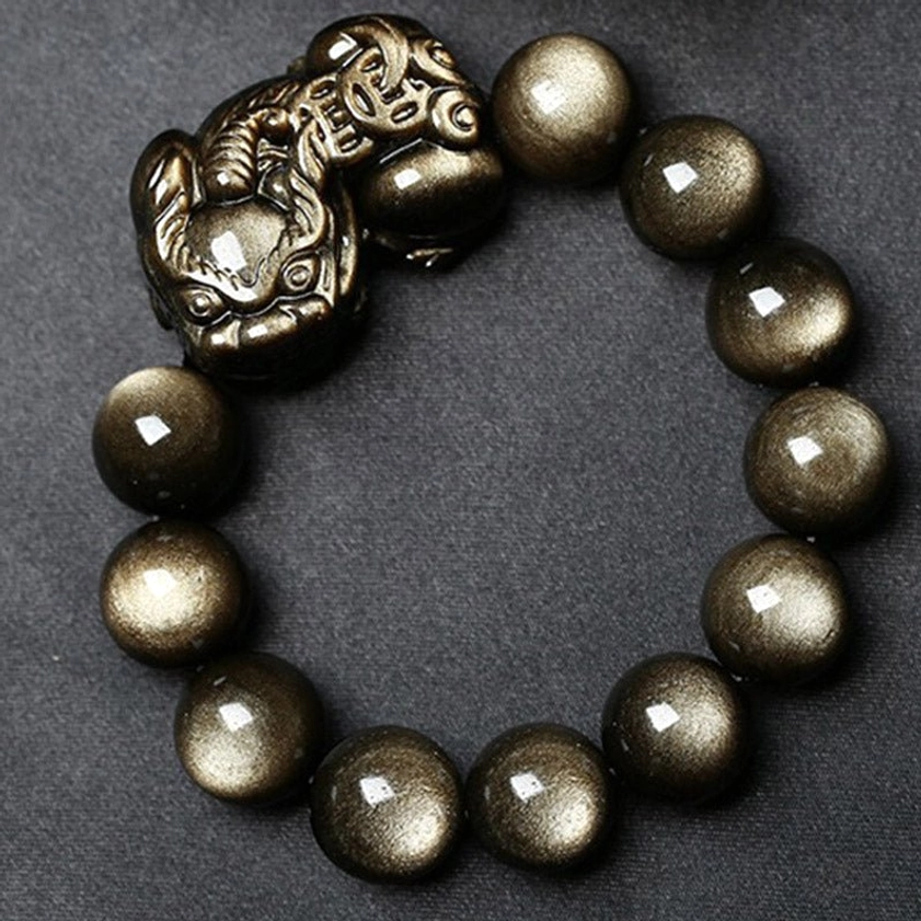 Golden obsidian Pixiu bracelet side view on black background highlighting stone texture and metal carving