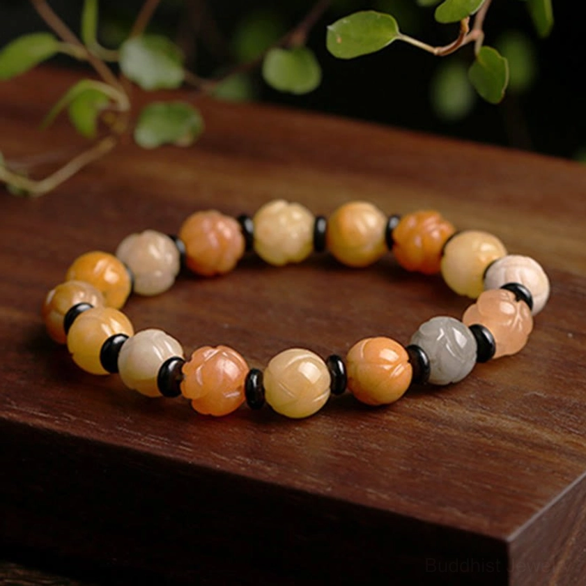 Single Golden Silk Jade Lotus Buddhist bracelet on rustic wooden table with natural green foliage background