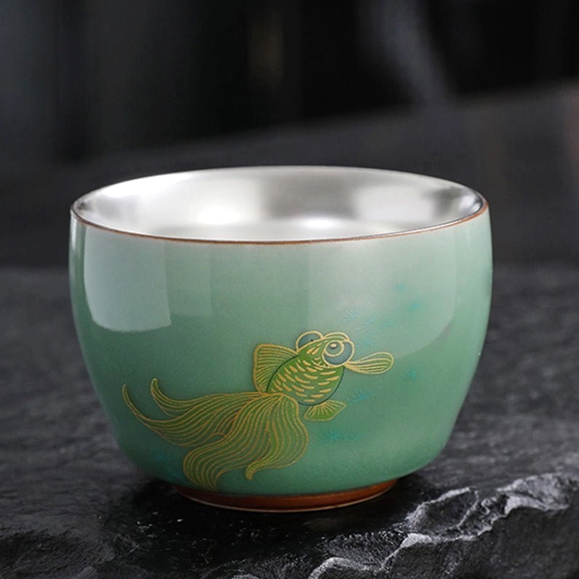 Goldfish koi design celadon tea cup with silver interior showing hand-painted aquatic Buddhist motif
