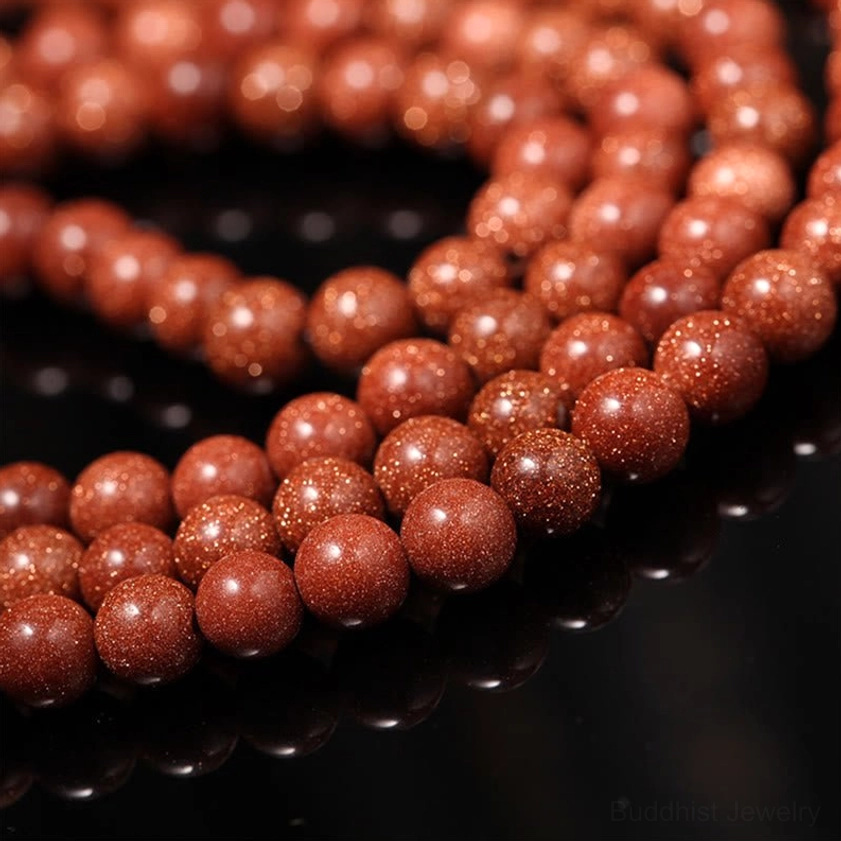 Macro shot of goldstone prayer beads showing dense sparkly reddish-brown stone texture and shine