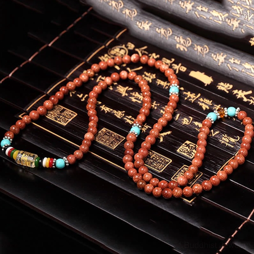Two goldstone mala bracelets arranged on vintage Chinese calligraphy wooden scroll background