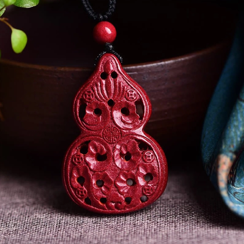 Gourd cinnabar Buddhist necklace pendant with carved gourd design on wine-red stone displayed in spiritual setting