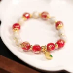 Red and white Liuli glass bead bracelet with gold gourd wealth charm pendant, featuring green gemstone accent and handmade incense ash porcelain beads for Buddhist prosperity