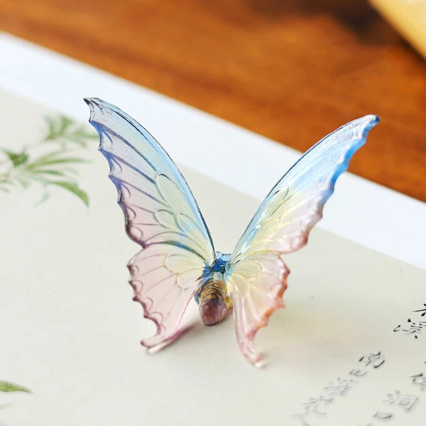 Flat lay front view of translucent gradient glass butterfly on Chinese painting desk