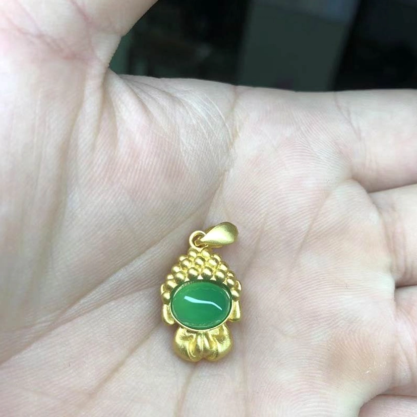 Green agate Buddha pendant held in hand - oval green agate stone with gold-plated metal setting