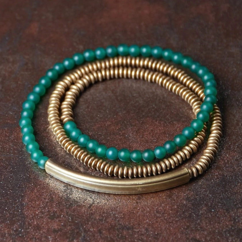 Green agate copper triple wrap Buddhist bracelet flat lay top-down view on dark rustic wooden surface with stacked wrap design showing prosperity and success energy