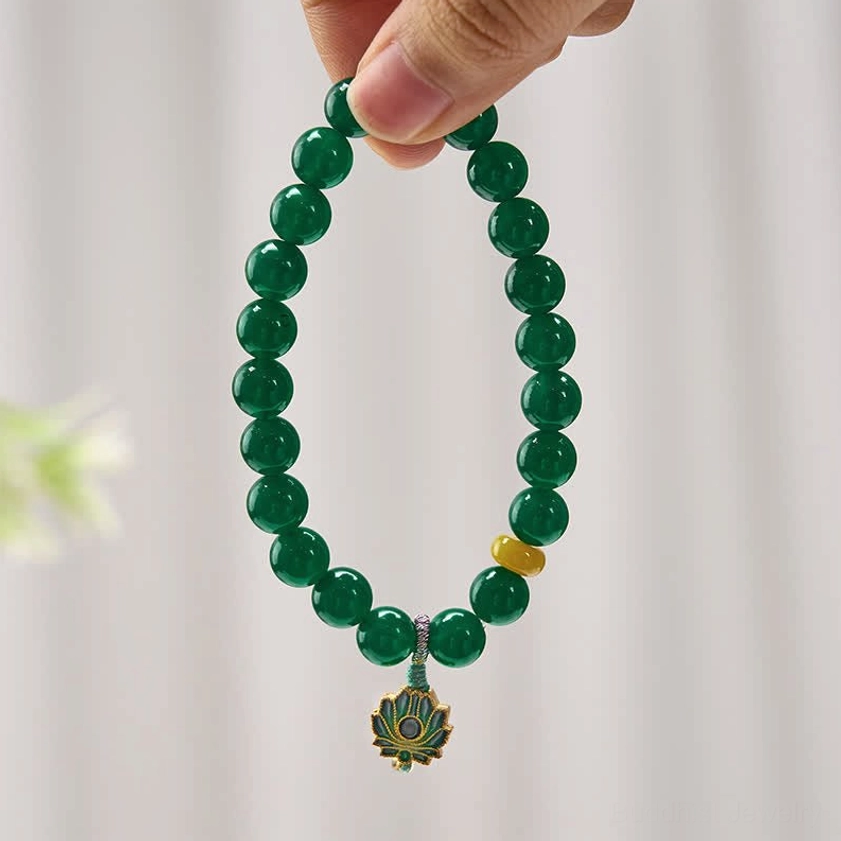 Close-up of green agate beaded bracelet held in fingertips displaying round polished beads, yellow accent bead, and detailed metal lotus charm