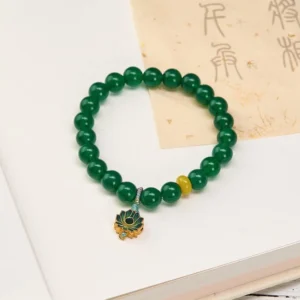 Green agate lotus charm beaded bracelet with yellow agate accent, displayed flat on vintage calligraphy paper showing authentic natural stone details