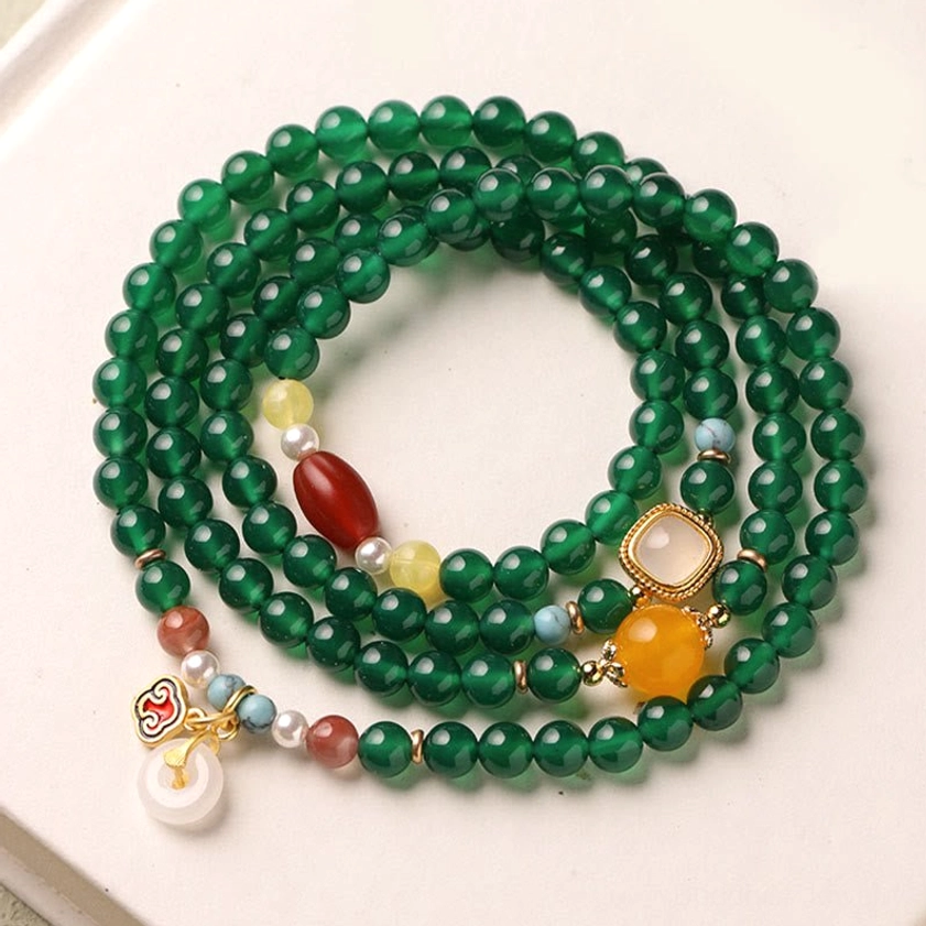 Green agate mala bracelet with full set of decorative pendants and peace buckle displayed from above