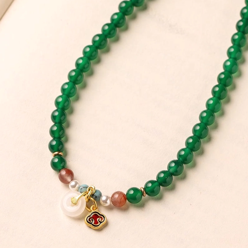 Single-strand green agate mala with peace buckle pendant and mixed gemstone accents in flat lay