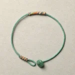 Green aventurine Buddhist braided string bracelet with 8mm beads and woven trim detail, top-down flat lay view