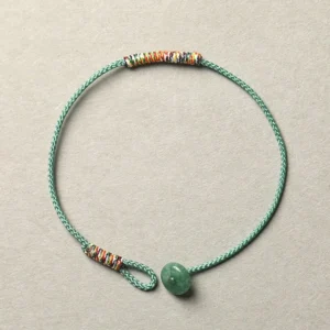 Green aventurine Buddhist braided string bracelet with 8mm beads and woven trim detail, top-down flat lay view