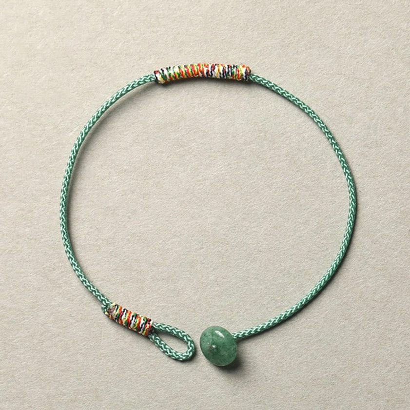 Green aventurine Buddhist braided string bracelet with 8mm beads and woven trim detail, top-down flat lay view
