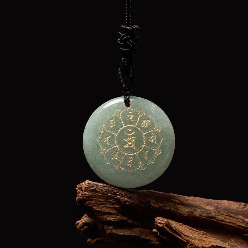 Green Aventurine Om Mani Padme Hum Buddhist pendant with gold Sanskrit mantra on reflective white surface