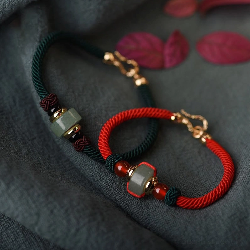 Green aventurine and red agate Buddhist luck bracelet with gold charm, flat lay displaying braided string design and bead details