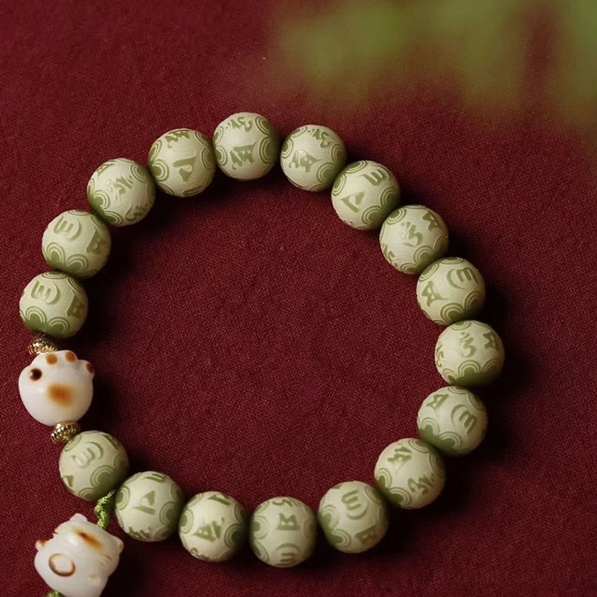 Large flat lay overhead view of green Bodhi seed bracelet with clear mantra engravings on each bead and cat paw decoration