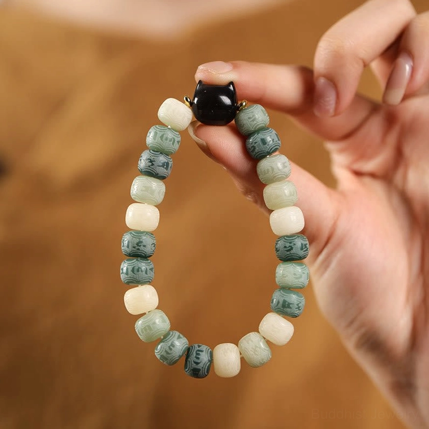 Green bodhi seed bracelet with cat head charm held in hand, showing texture and bead quality of spiritual jewelry