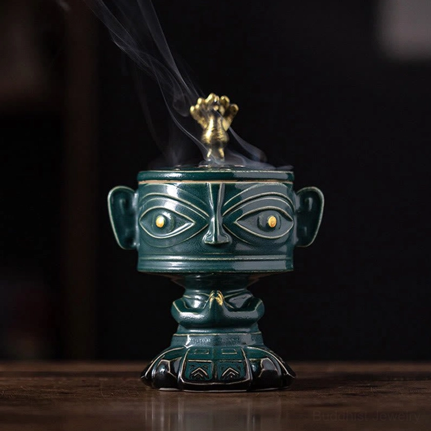Green Buddhist ceramic incense burner with natural ceramic patina, front view on wooden surface