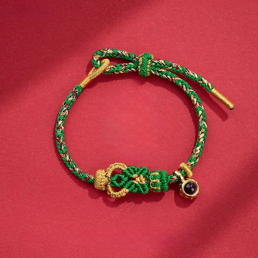 Green Buddhist string bracelet hand-woven with decorative Buddha knot and protective black bead