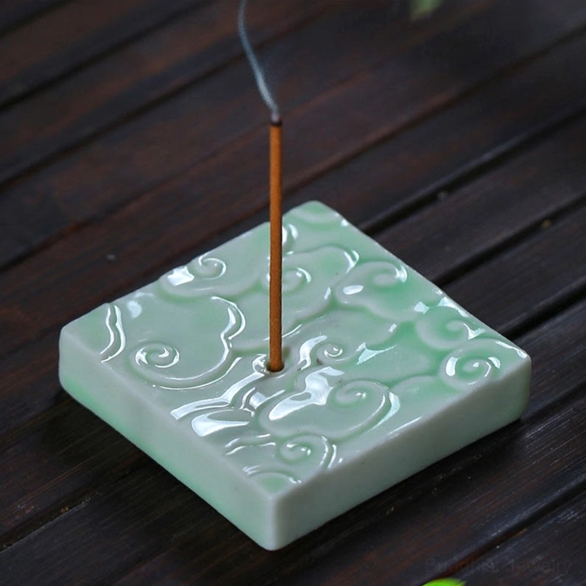 Celadon green ceramic square cloud incense burner on wooden table, high-angle view showing embossed cloud detail, glossy glaze, and lit incense with fragrant smoke rising