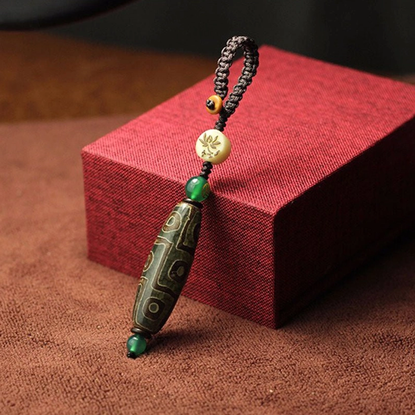 Green agate dzi bead keychain with floral pattern bead and green spacer beads showing Buddhist amulet craftsmanship and natural stone detail