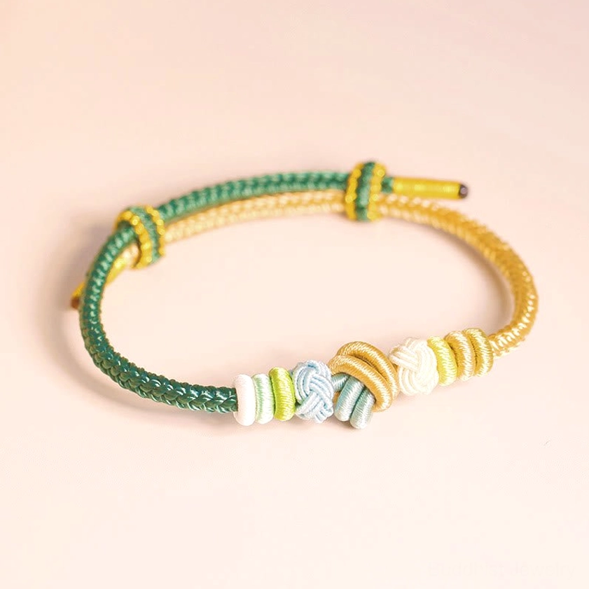 Green and gold eight-thread peace knot Buddhist bracelet flat overhead view with warm background