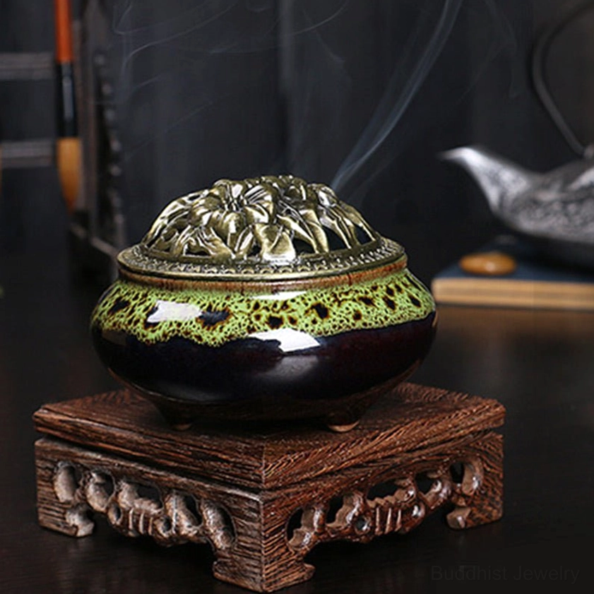 Green speckled ceramic incense burner displayed on carved wooden stand with tea ceremony props