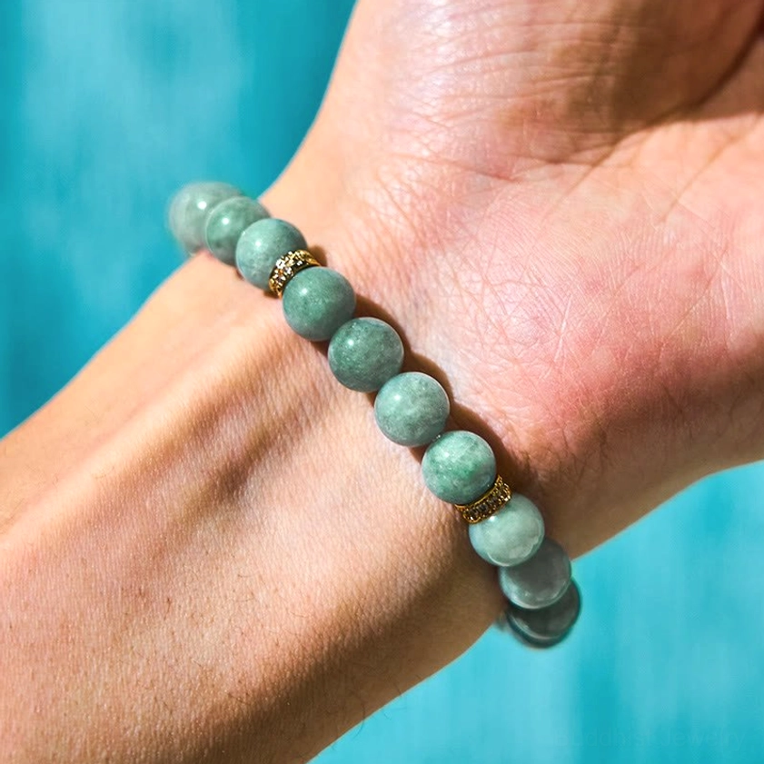 Natural green jade beads Buddhist prayer bracelet worn on wrist with gold crystal spacers and rotating charm in close-up view
