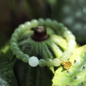 Green jade lotus bracelet with 7mm round beads and gold lotus charm, top-down view on lotus pod