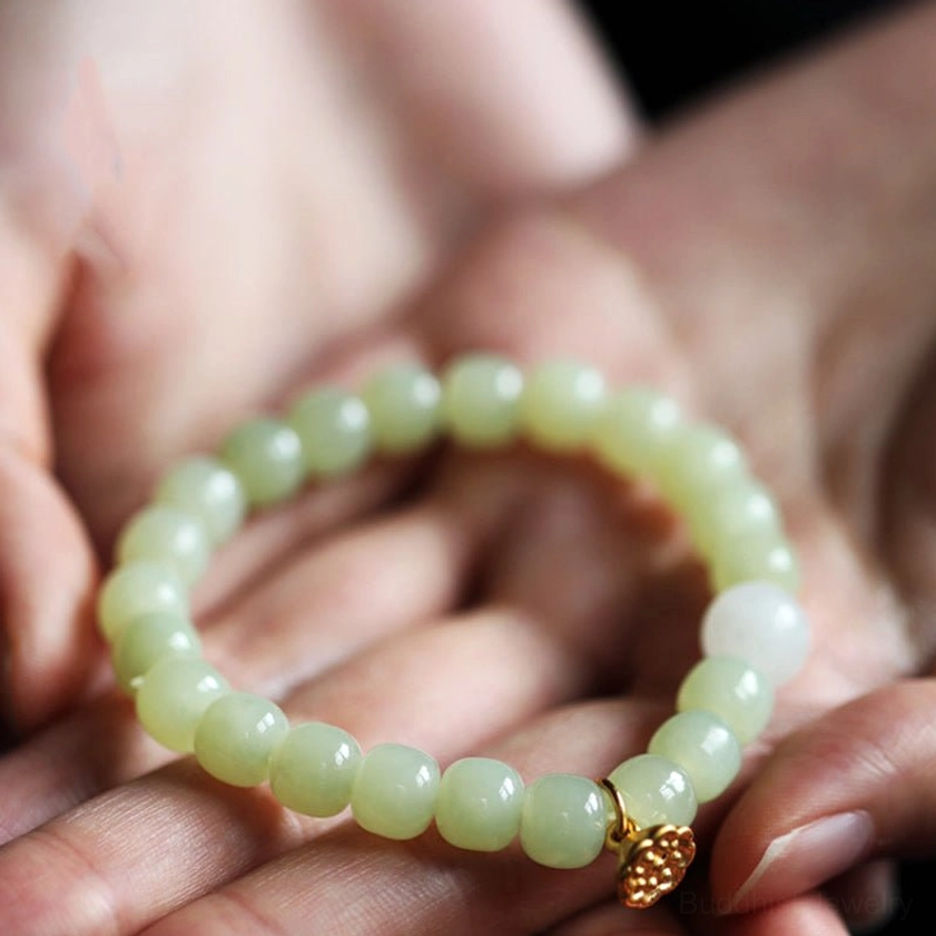Light green jade prosperity bracelet held in hands, showing smooth matte beads and lotus charm