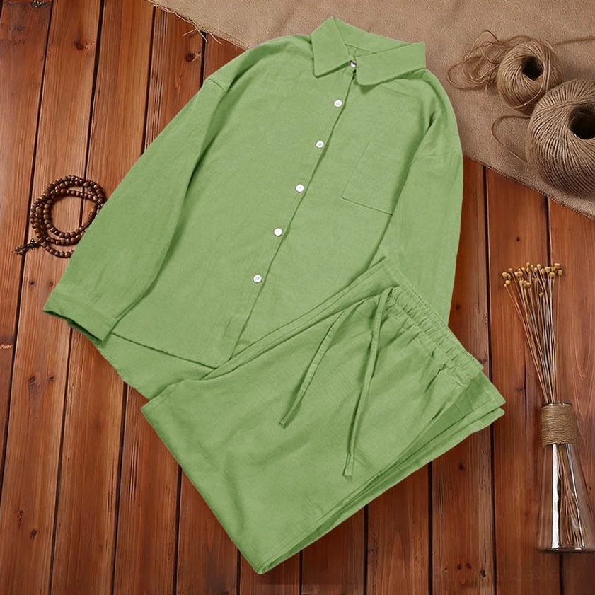 Green cotton meditation clothing set flat lay on wooden table with mindful lifestyle props