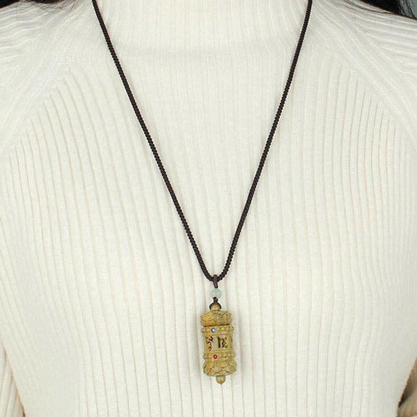 Woman wearing adjustable braided green sandalwood Buddhist pendant necklace over white knitted sweater, wearable close-up shot