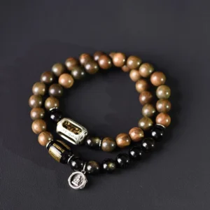 Green sandalwood and gold sheen obsidian double wrap Buddhist bracelet with engraved copper Buddha pendant, flat lay top view