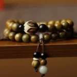 Green sandalwood bodhi seed lotus double wrap bracelet close-up overhead view on wooden shelf display with carved lotus bead and tassel