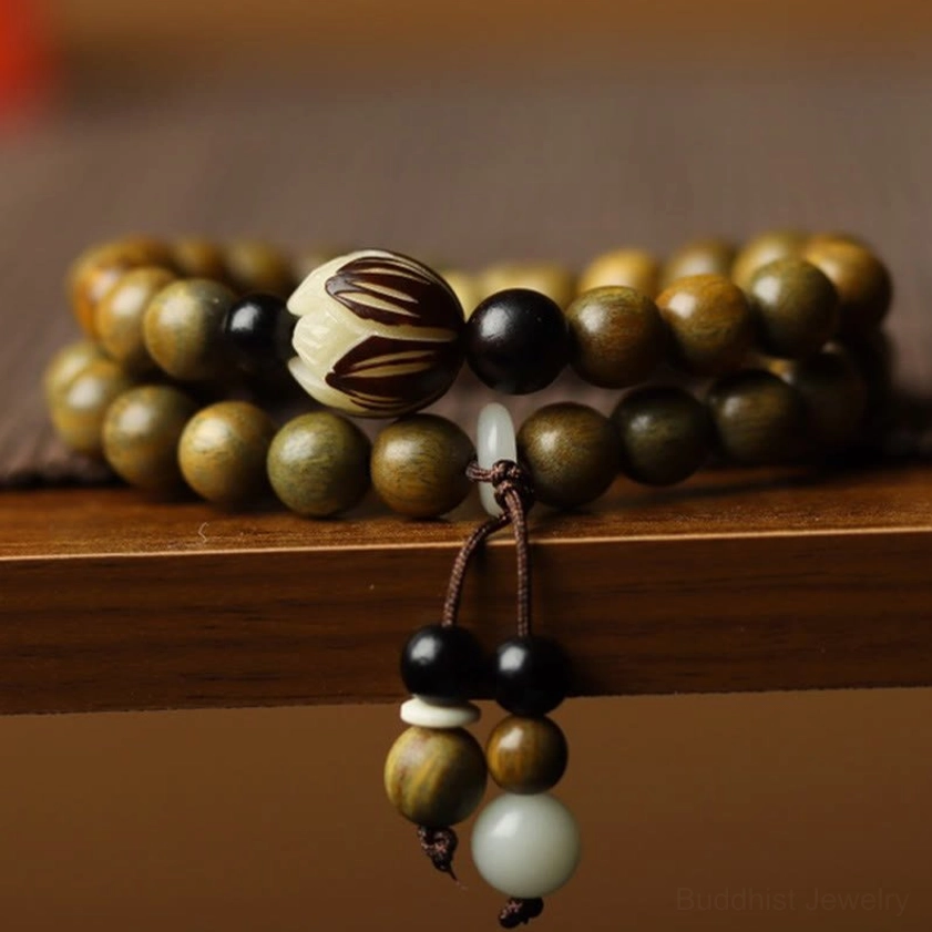 Green sandalwood bodhi seed lotus double wrap bracelet close-up overhead view on wooden shelf display with carved lotus bead and tassel