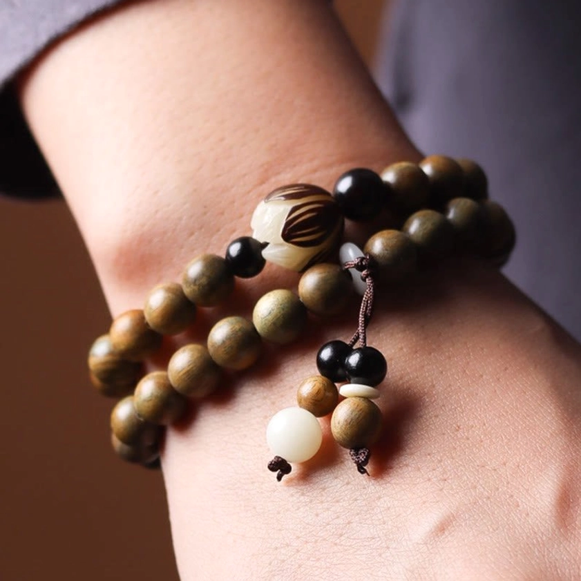 Worn on wrist green sandalwood bodhi lotus double wrap bracelet showing fitted design with mixed accent beads and lotus tassel