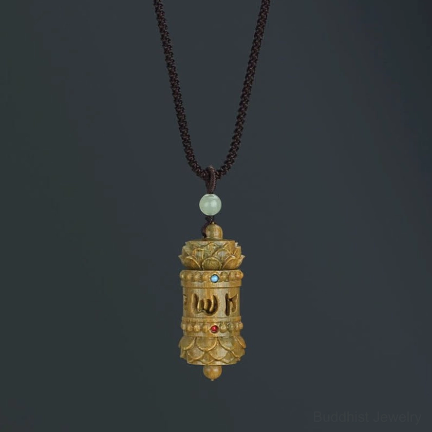 Green sandalwood Om Mani Padme Hum Buddhist prayer wheel pendant necklace with carved mantra script and lotus design on dark background