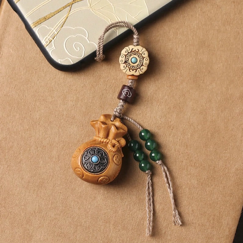 Green sandalwood Om Mani Padme Hum keychain showing natural color transformation and wood characteristics