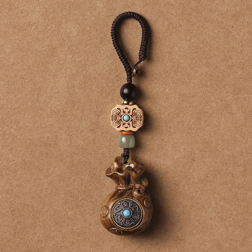 Green sandalwood Om Mani Padme Hum keychain with carved floral beads and braided rope flat lay view