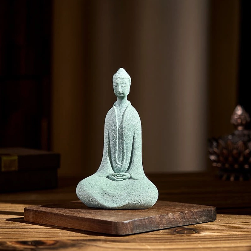 Handcrafted Buddha figurine positioned on wooden desktop with complementary spiritual decorative elements