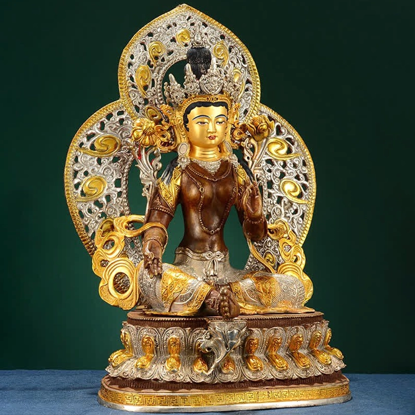 Three-quarter front view of Green Tara Bodhisattva statue showing scroll-patterned back aureole and mixed metal finish